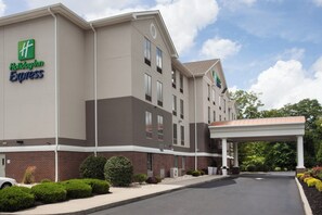 A Holiday Inn Express hotel with a brick facade, multiple windows, and a covered parking area. - Holiday Inn Express Haskell - Wayne Area by IHG (Wanaque)