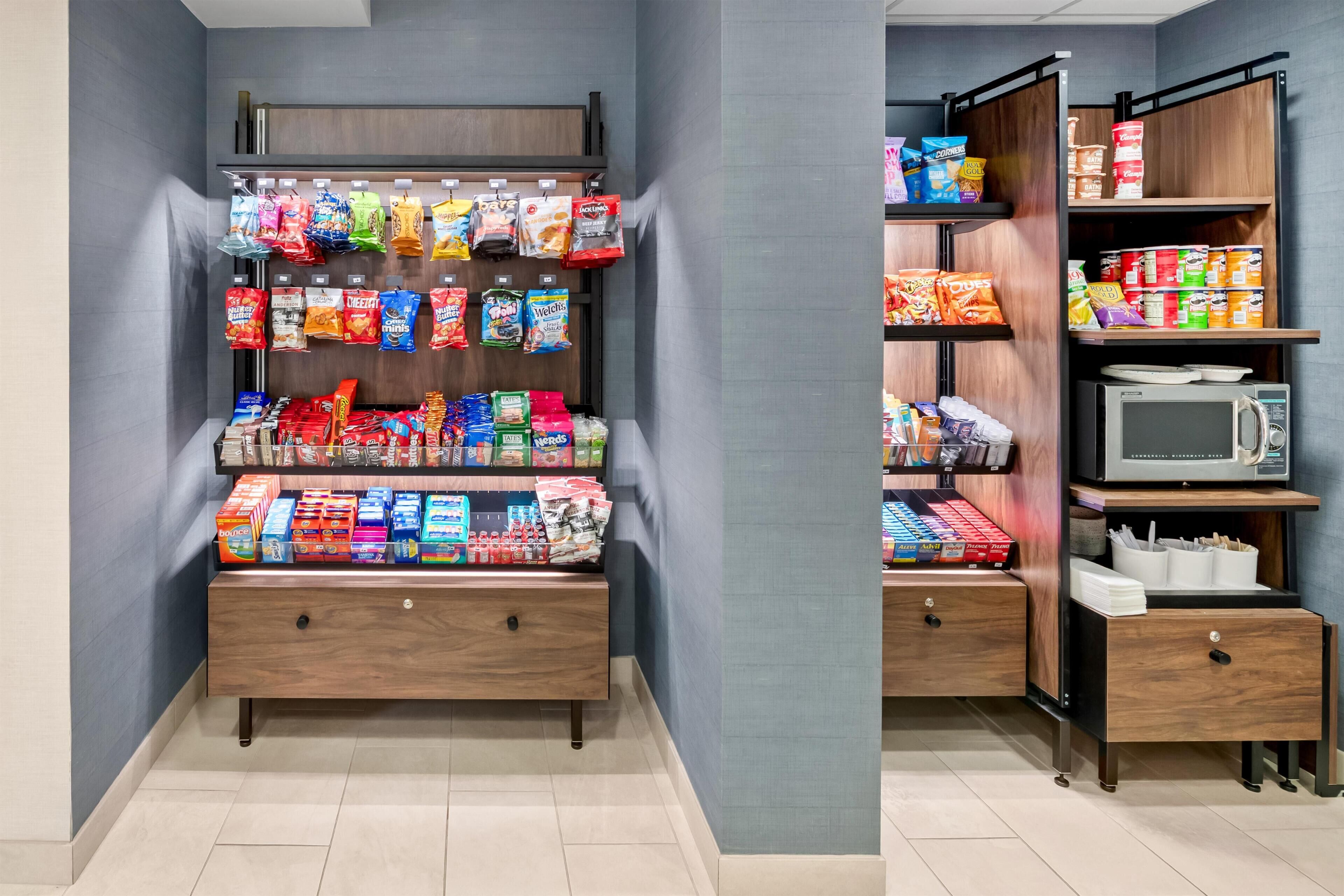 A snack vending machine with various packaged snacks and a microwave.