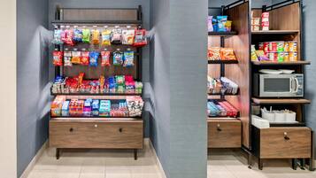 A snack vending machine with various packaged snacks and a microwave.