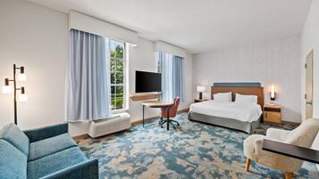 Une chambre d’hôtel avec un lit, un bureau, une chaise, une télévision et une fenêtre avec des rideaux.