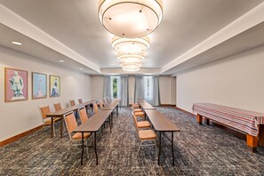 Un salón de conferencias con mesas largas, sillas y un banco.