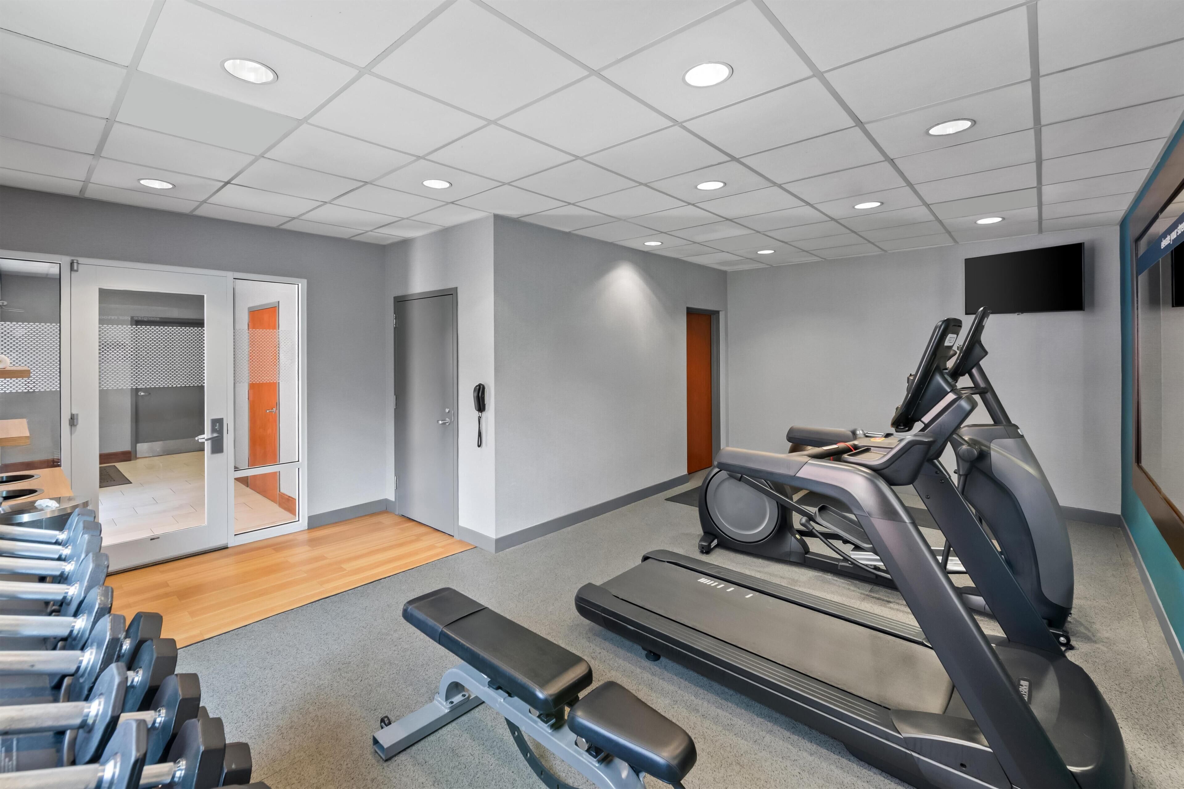 A gym with treadmills, a bench, and dumbbells.