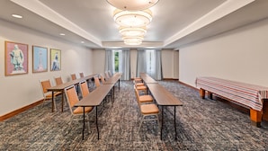 A conference room with long tables, chairs, and a bench.