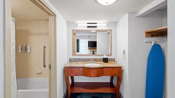 Een badkamer met een houten wastafelmeubel, een spiegel, een handdoekrek en een blauwe douchebak.'