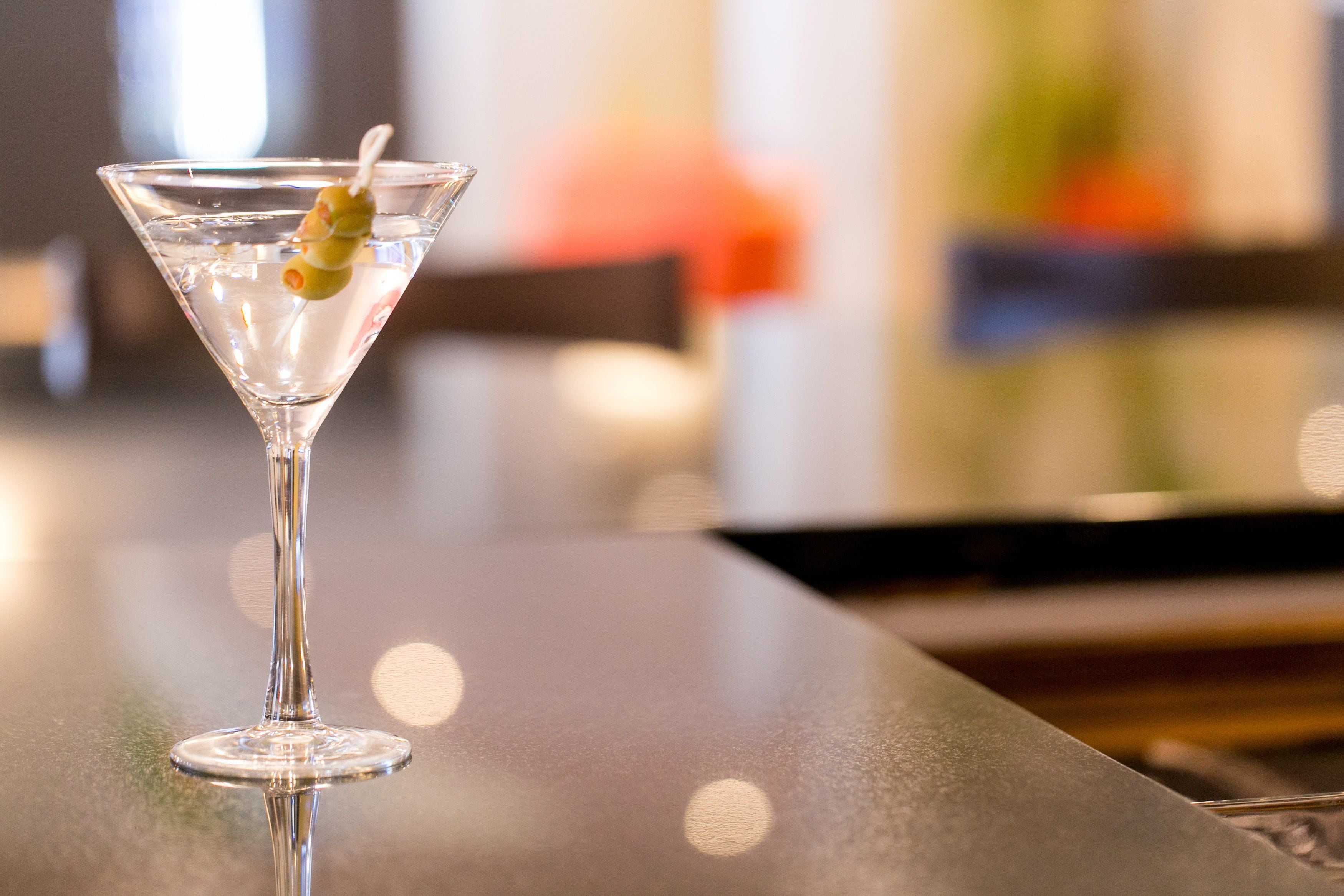 A martini glass with a lime garnish on a reflective surface.
