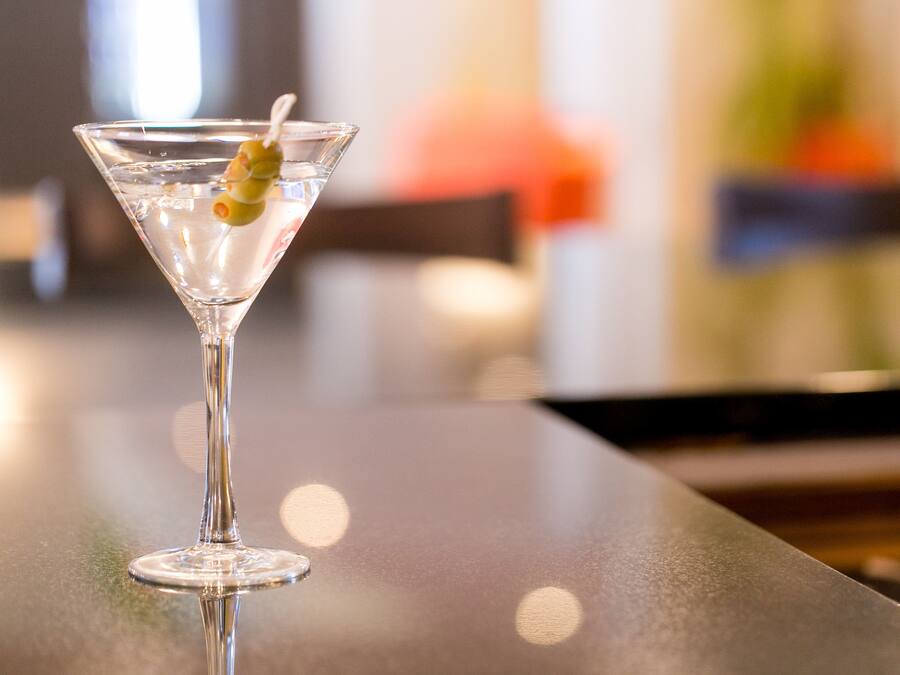 Una copa de martini con una rodaja de lima sobre una superficie reflectante.