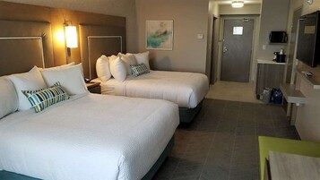 Habitación de hotel con dos camas, televisión, microondas y una kitchenette pequeña.