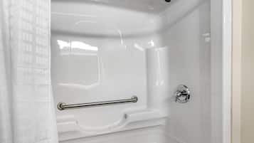 Un baño moderno con bañera, ducha y barra de apoyo.