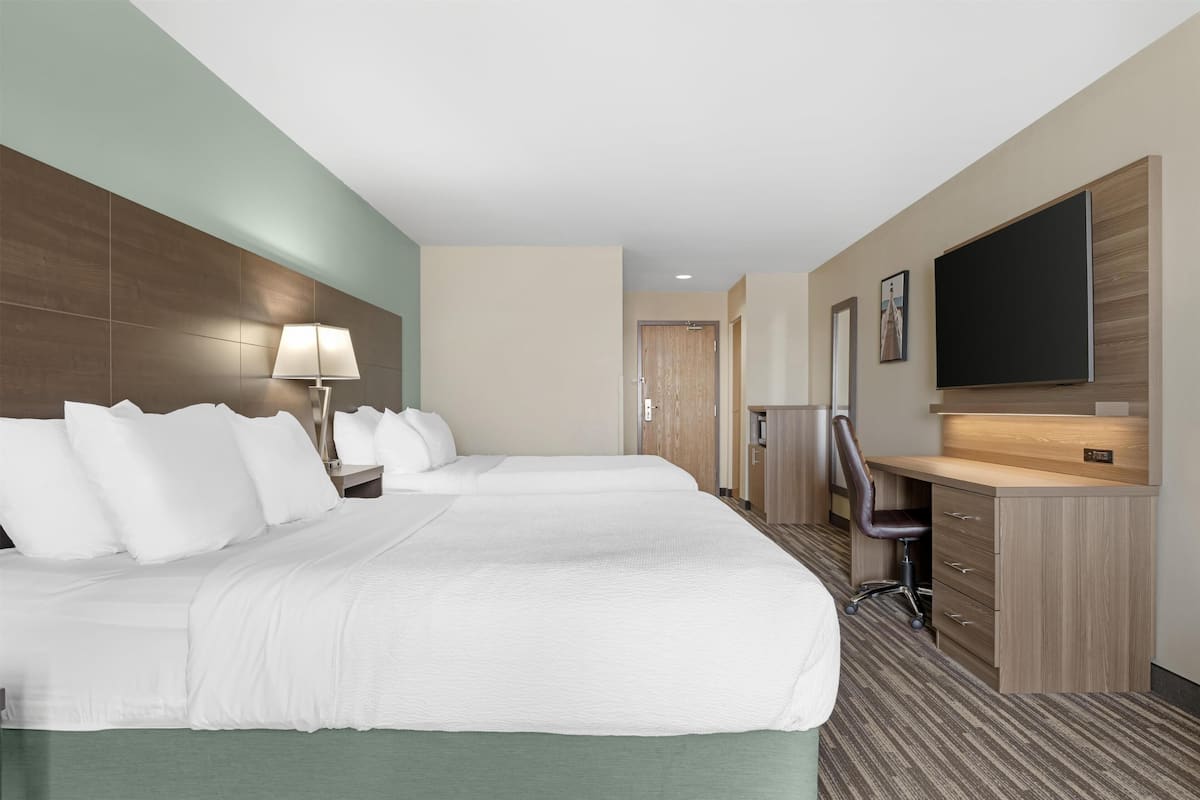 Een hotelkamer met een groot bed, een bureau, een stoel, een televisie en een deur naar de badkamer.