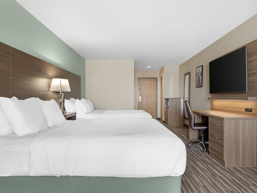 Habitación de hotel con una cama grande, un escritorio, una silla, un televisor y una puerta que da al baño.