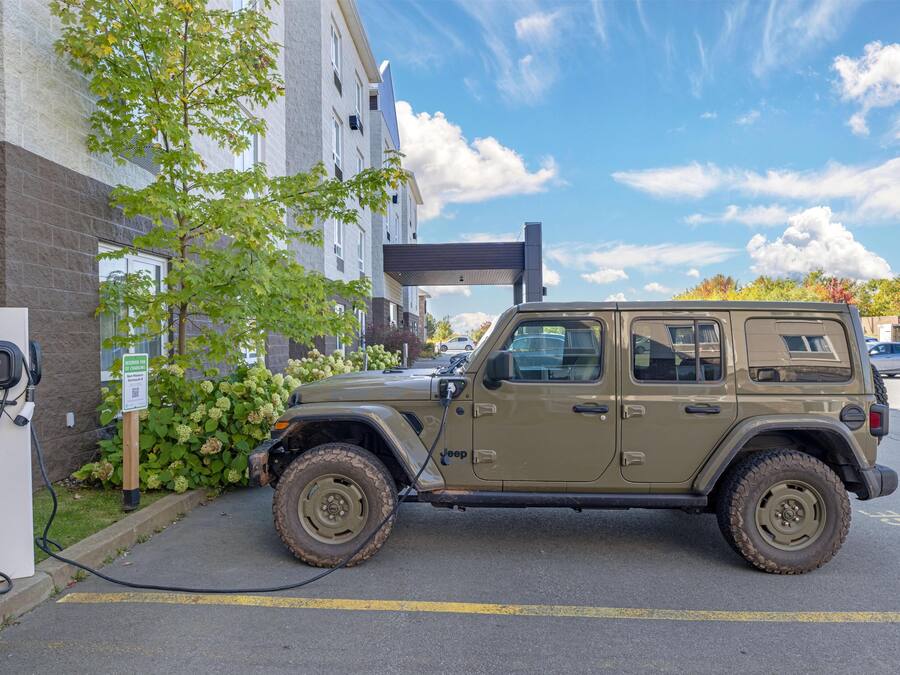 A Jeep parked at an electric charging station in a parking lot.