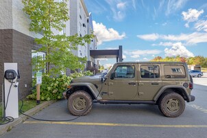 Un Jeep estacionado en una estación de carga eléctrica en un estacionamiento.