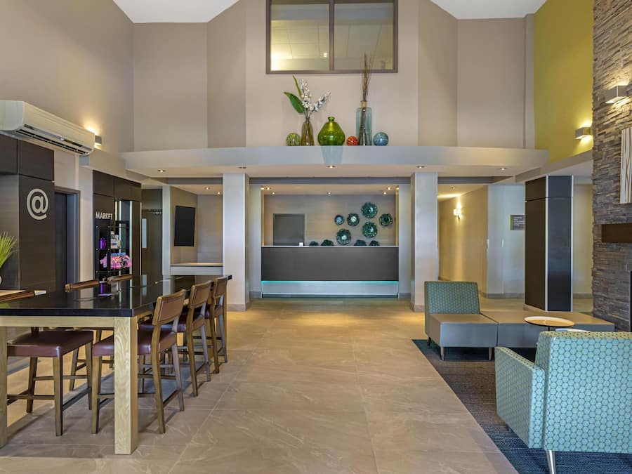Un vaste espace de vie doté d’un haut plafond, d’une table à manger avec des chaises, d’une cheminée et d’un coin salon agrémenté d’un pouf à motifs.