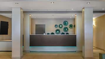 A reception area with a modern design, featuring a central desk, decorative wall art, and a flat-screen TV.