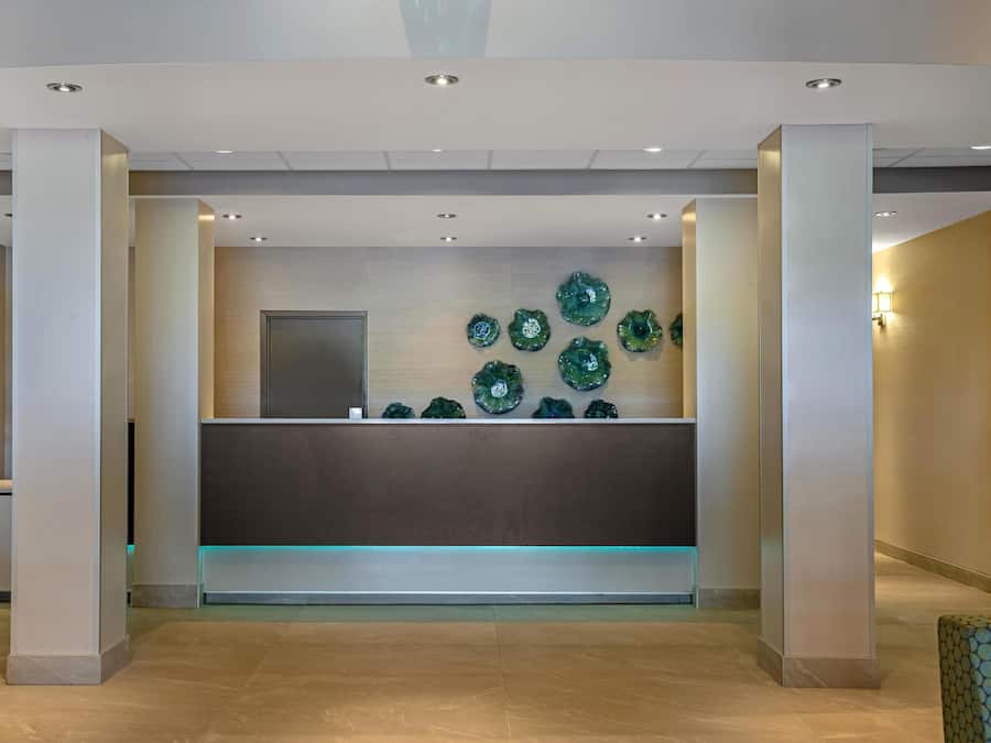 A reception area with a modern design, featuring a central desk, decorative wall art, and a flat-screen TV.