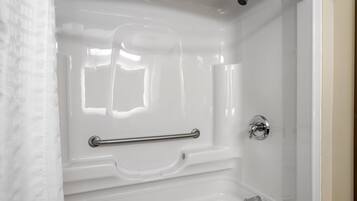 A white bathtub with a grab bar, a showerhead, and a faucet.