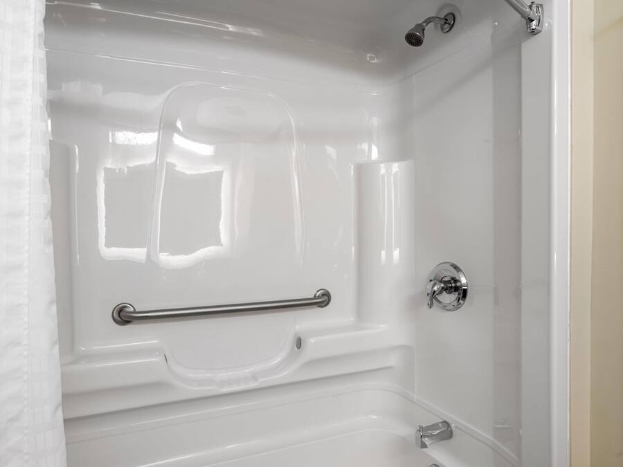A white bathtub with a grab bar, a showerhead, and a faucet.
