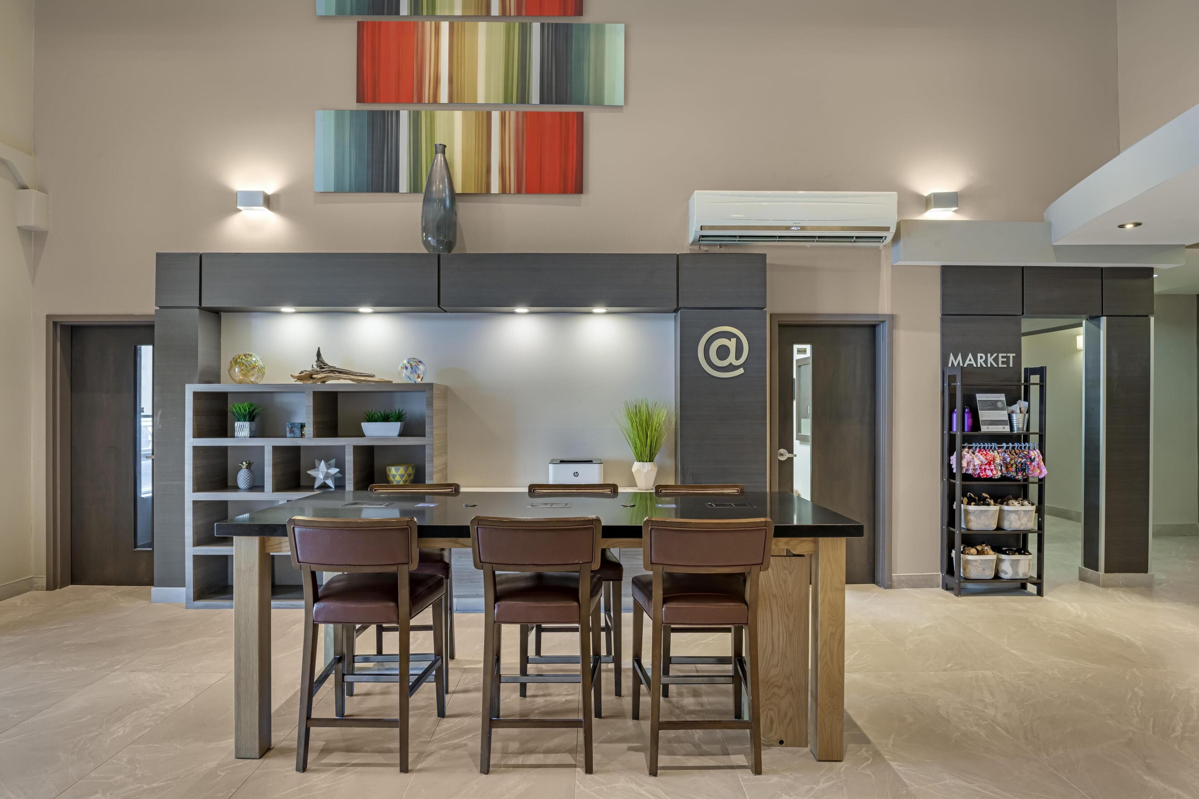 A modern kitchen with a dining area, featuring a black countertop, wooden chairs, and a built-in shelf with decorative items.
