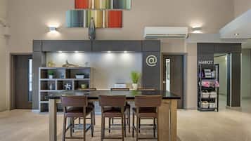A modern kitchen with a dining area, featuring a black countertop, wooden chairs, and a built-in shelf with decorative items.
