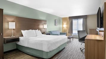 A hotel room with a large bed, a desk, a chair, a TV, and a window with curtains.