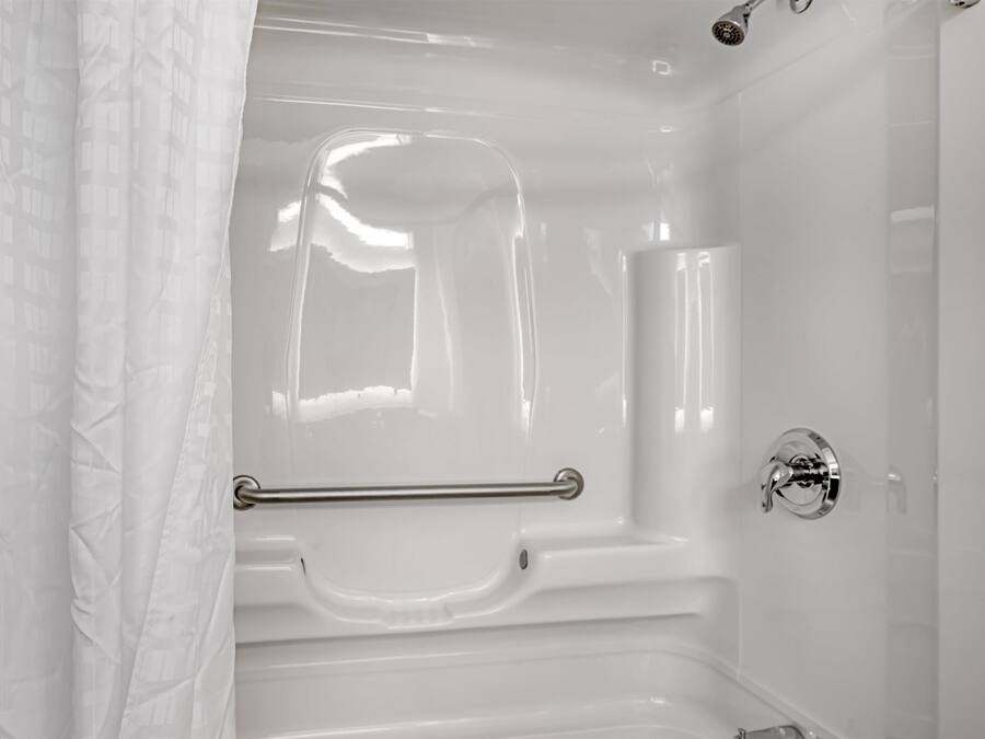 A white bathtub with a grab bar, a showerhead, and a chrome faucet.