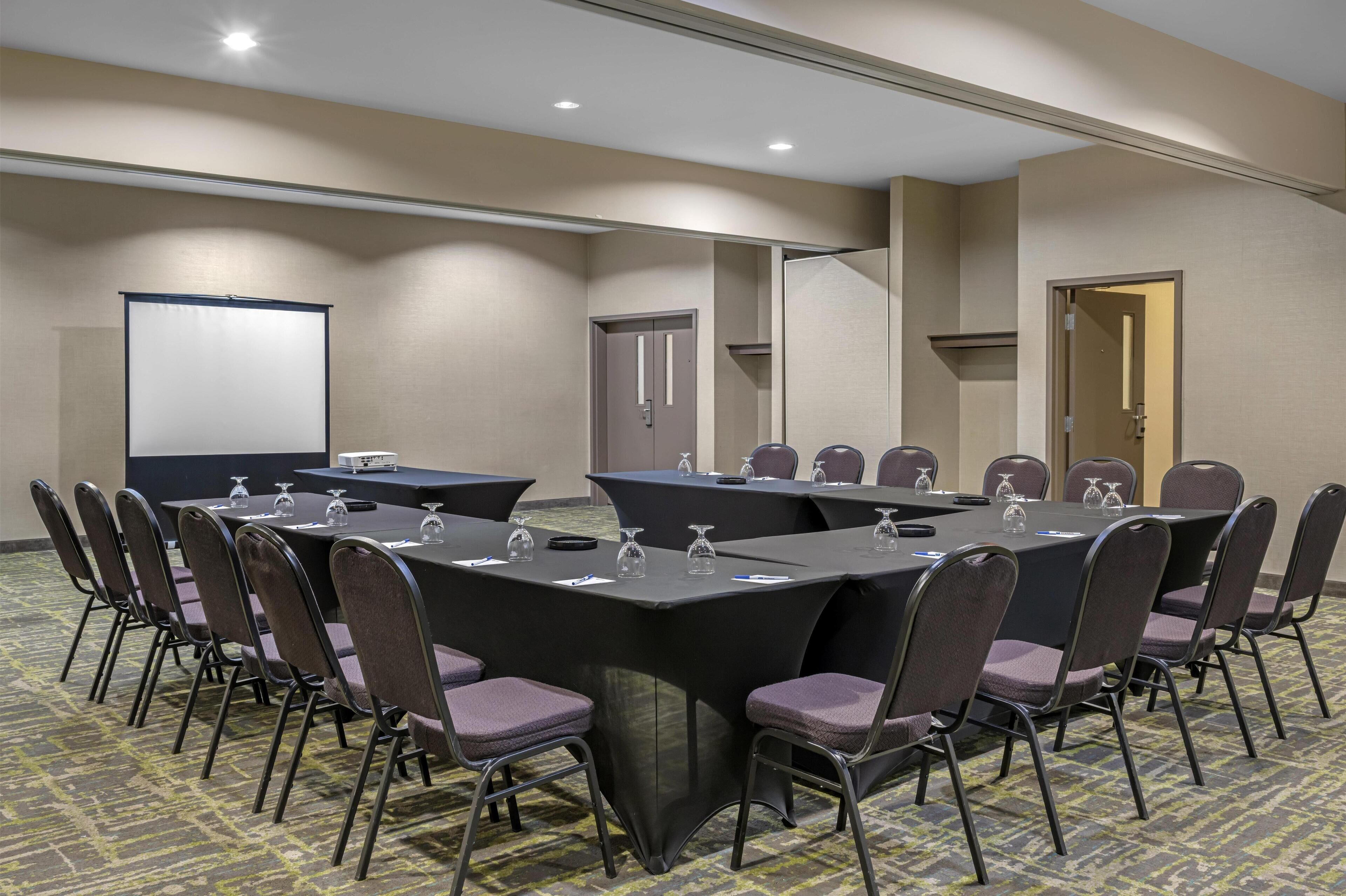 A conference room with a large table, chairs, and a projector screen.