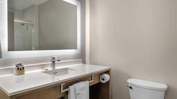 A modern bathroom with a white sink, mirror, and toilet.