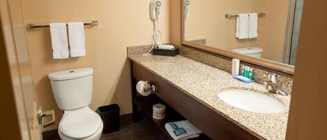 A hotel bathroom with a toilet, sink, towel rack, and a hairdryer.