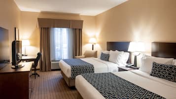 A hotel room with two beds, a desk, a chair, a TV, and a window with curtains.