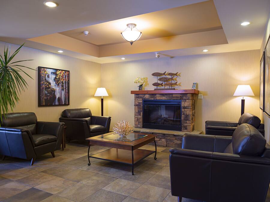 A modern living room with leather sofas, a glass coffee table, a fireplace, and two wall-mounted lamps.