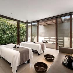 Relax in a serene space with a massage table, sofa, and lush views.
