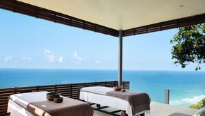 A room with two beds, a table with a teapot, and a view of the ocean. - Alila Villas Uluwatu, Bali (Pecatu)