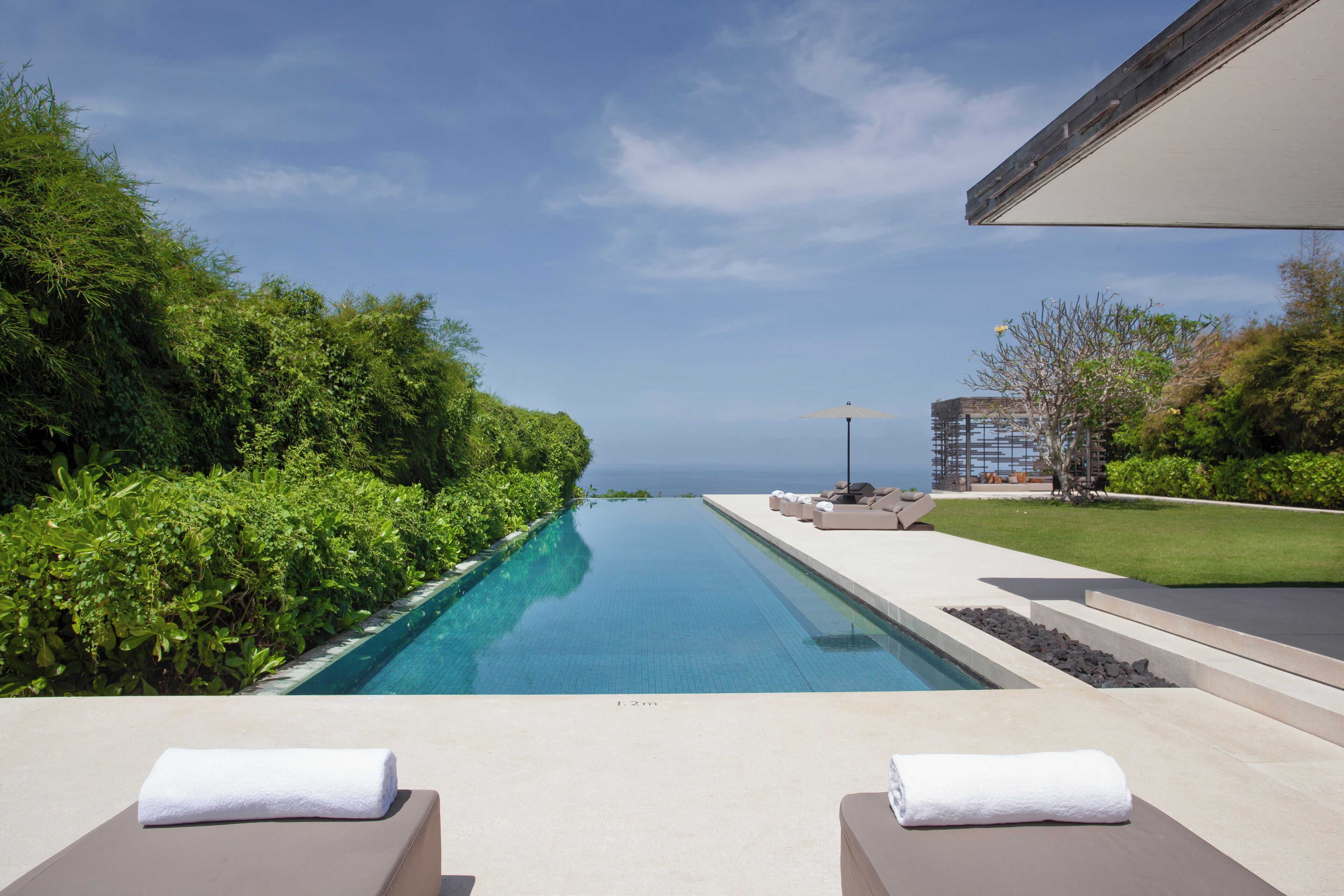 A pool with lounge chairs and a view of the ocean.