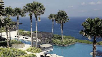 Un área de piscina con palmeras y vista al océano.