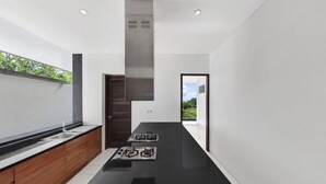 A modern kitchen with a black countertop, wooden cabinets, and a gas stove.