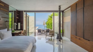 A modern bedroom with a large bed, a desk, and a view of the sea. - Alila Villas Uluwatu, Bali (Pecatu)