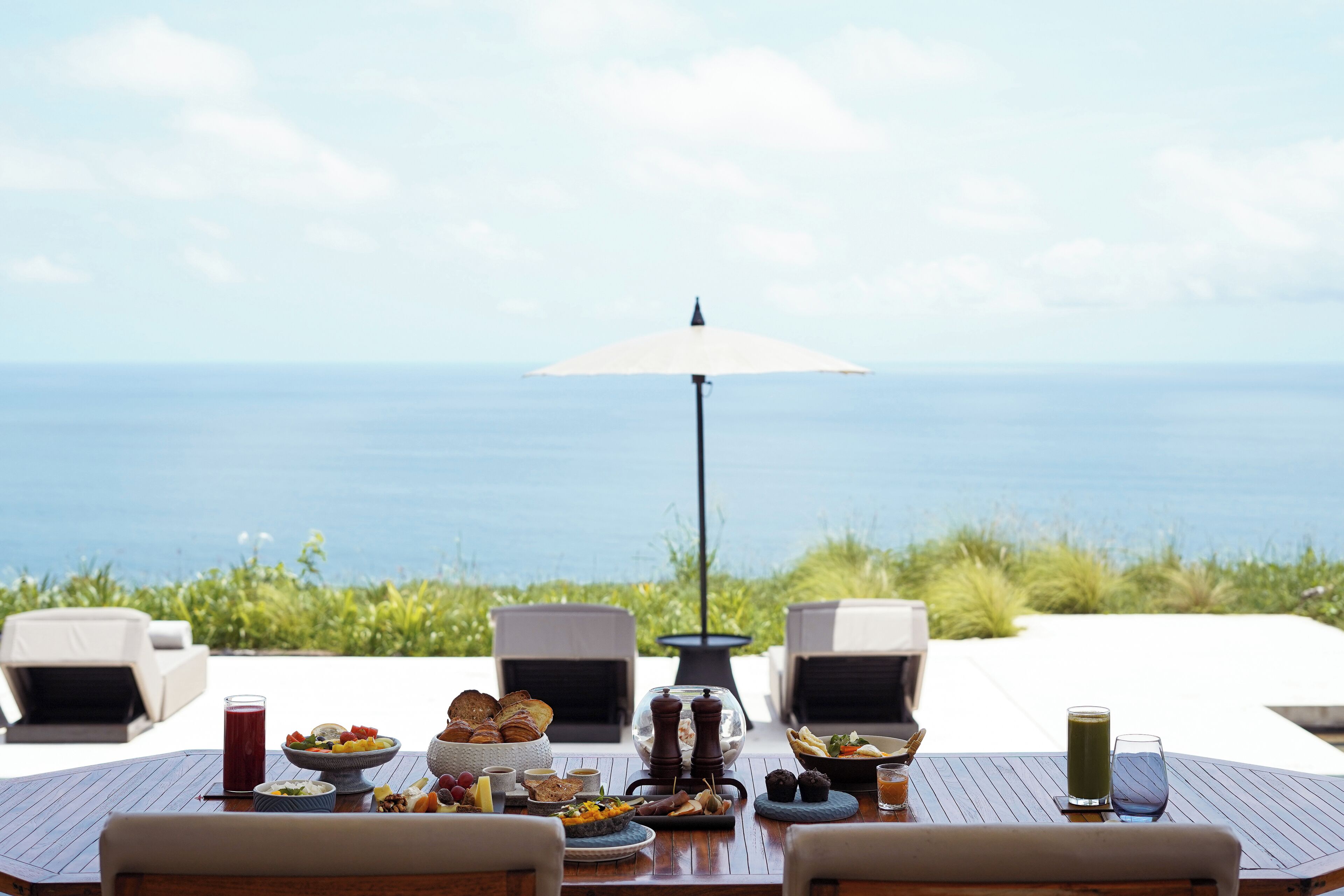 A table set with breakfast items and a view of the ocean.