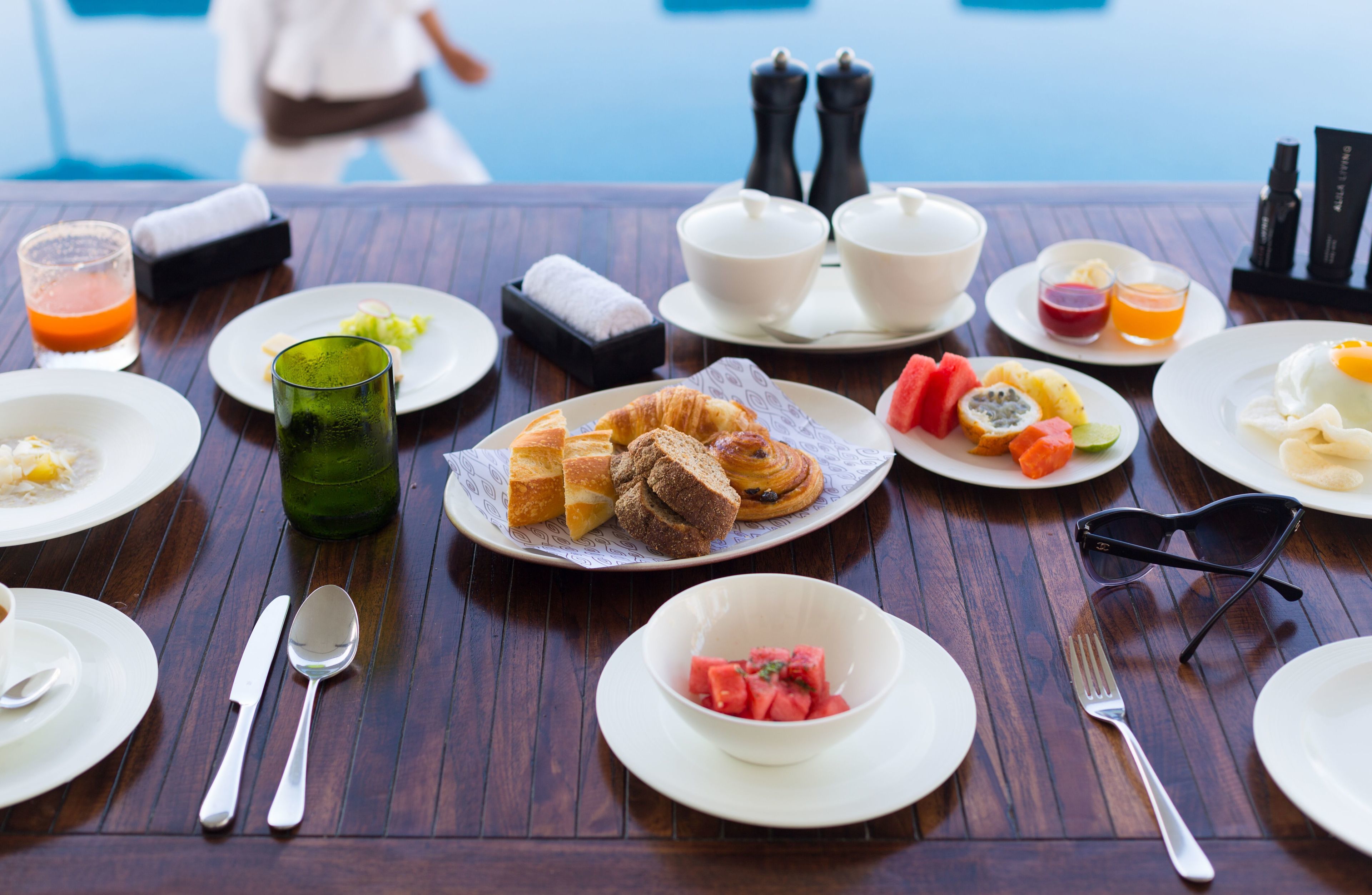 A breakfast table with various dishes, including croissants, fruits, and beverages.