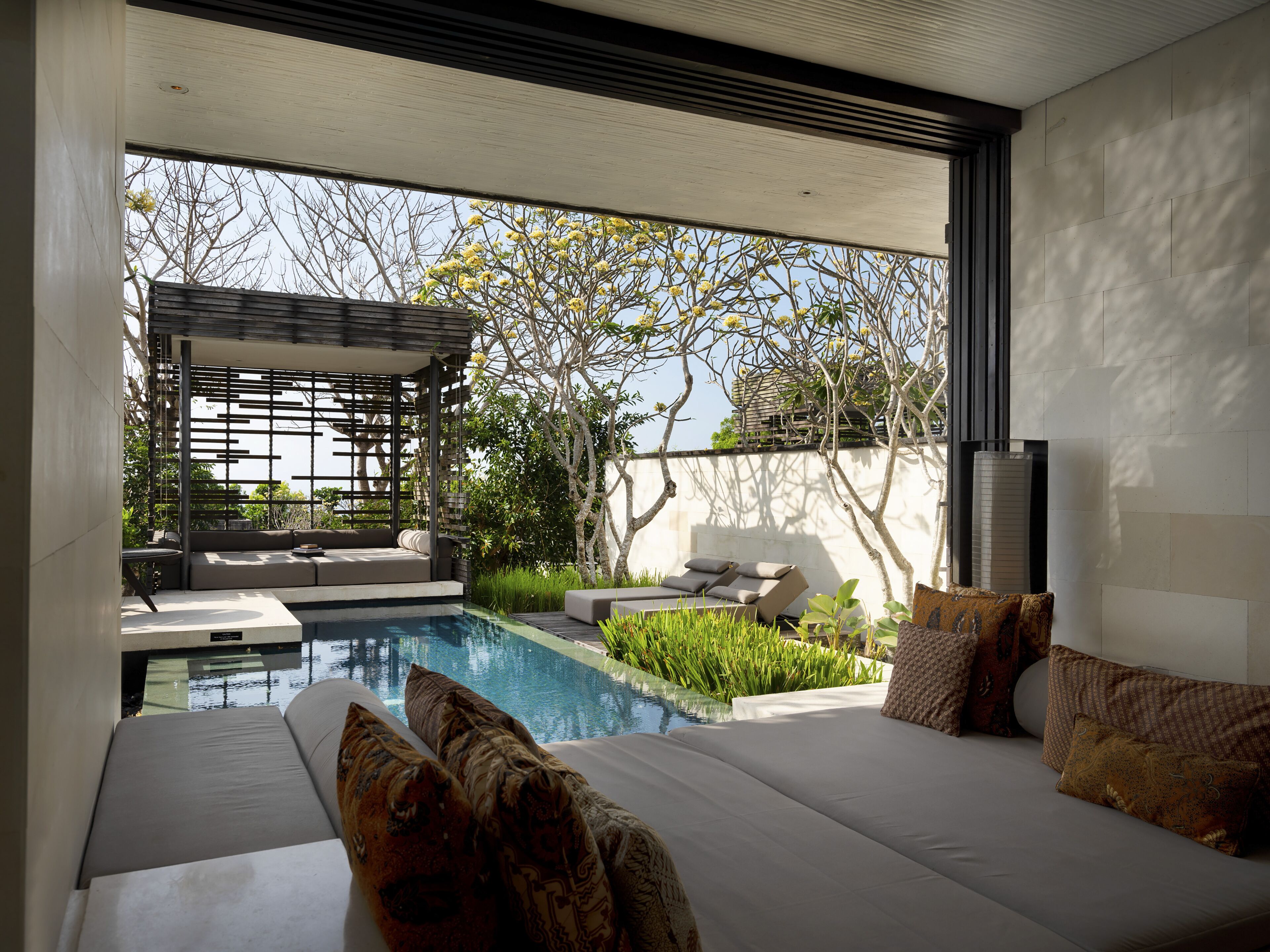 Un espacio al aire libre moderno con piscina, mobiliario y una pérgola.