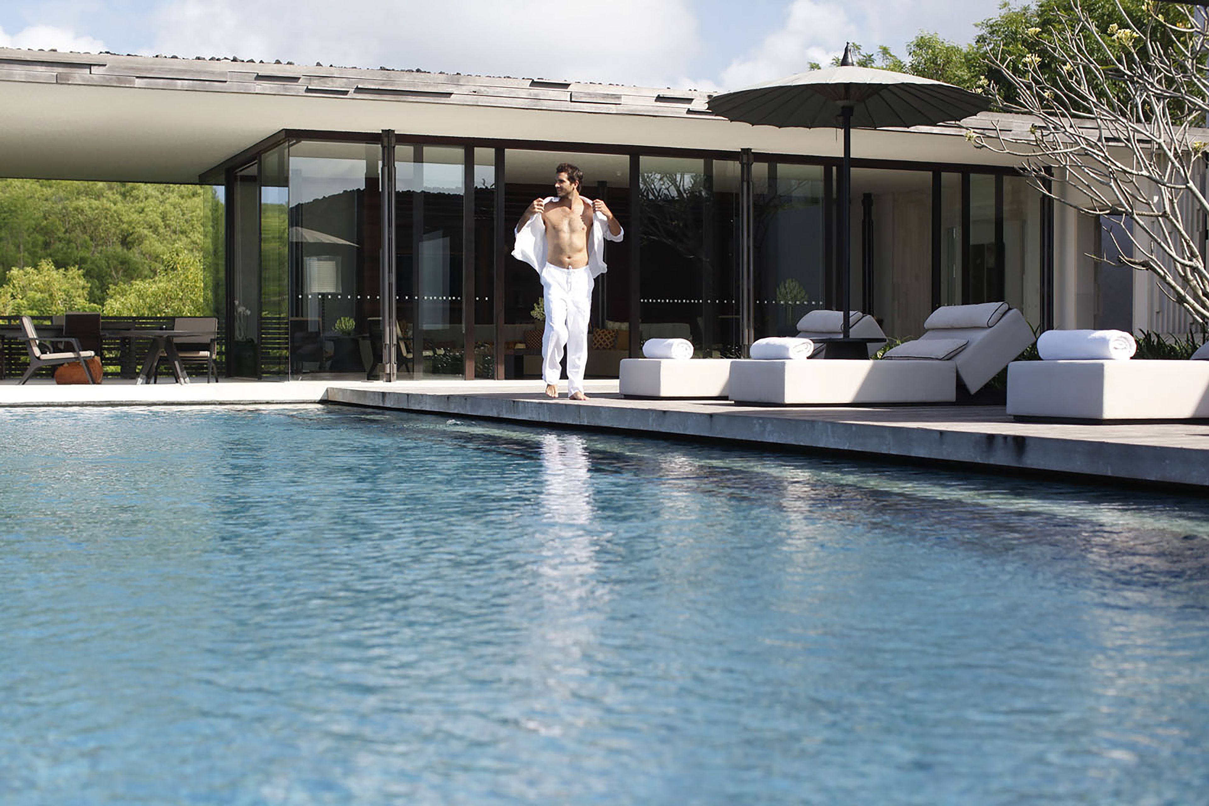 A modern pool area with a glass-enclosed lounge, a pool, and outdoor seating.