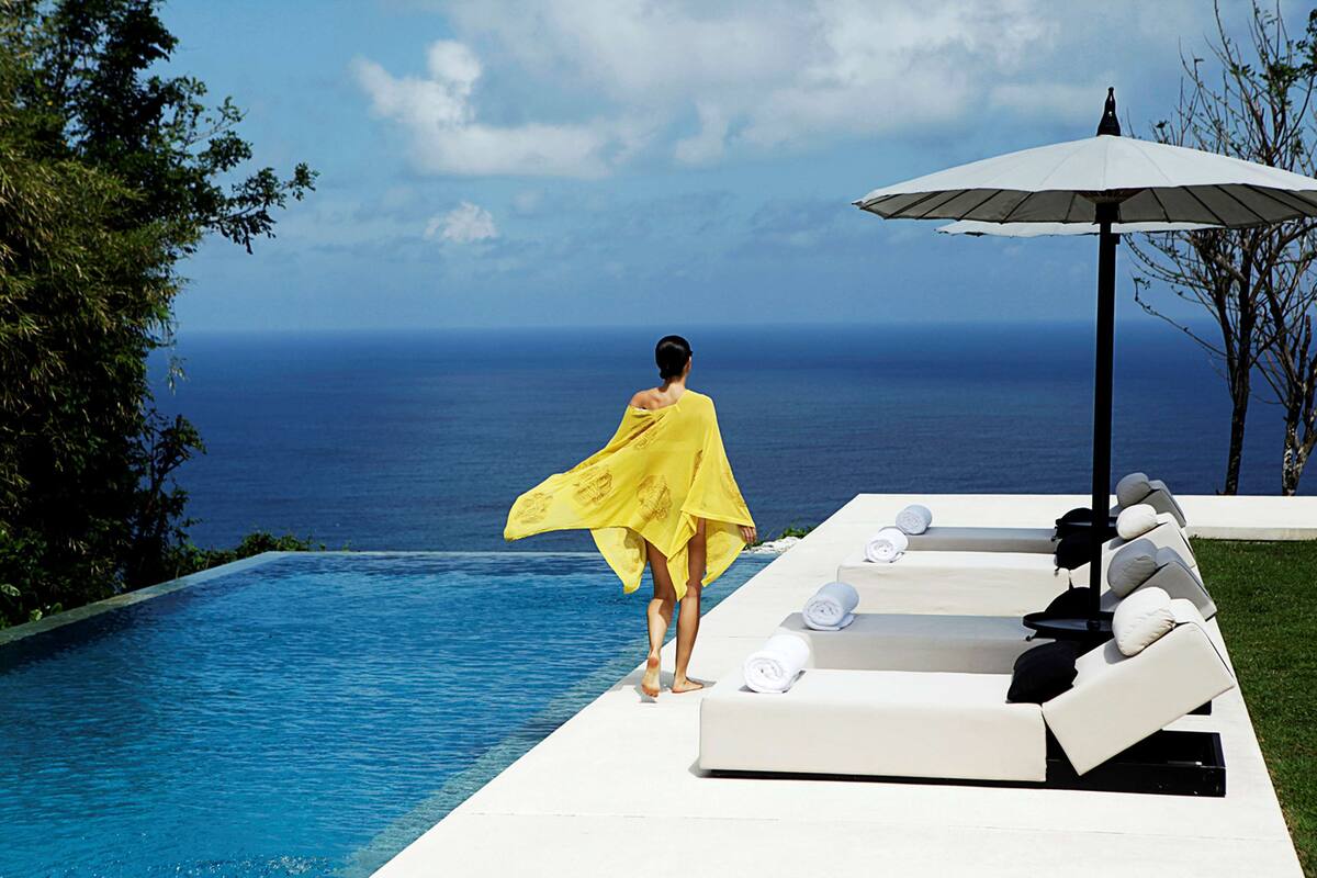 A poolside area with lounge chairs and an umbrella, overlooking a body of water.