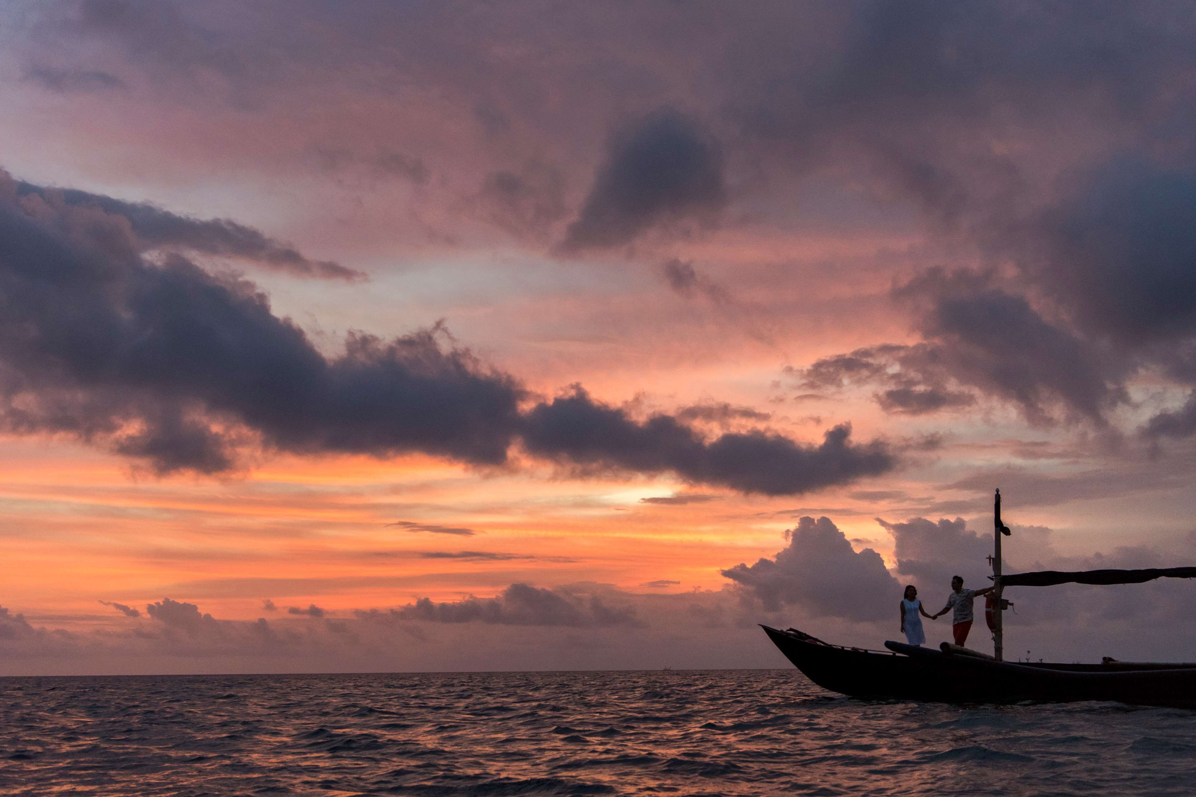 A sunset over the ocean with a boat carrying two people.