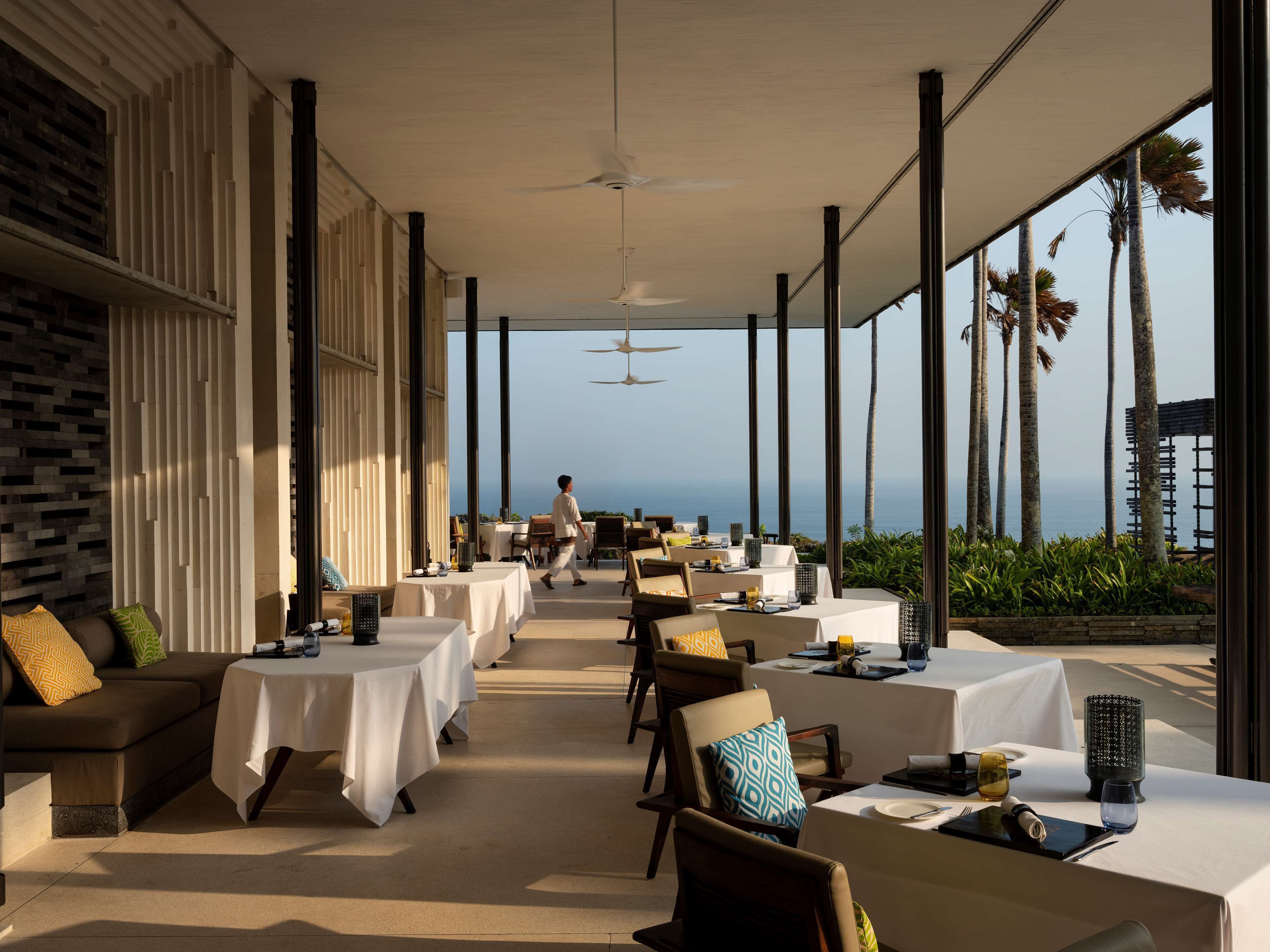 A restaurant with tables set for dining, overlooking a scenic ocean view.