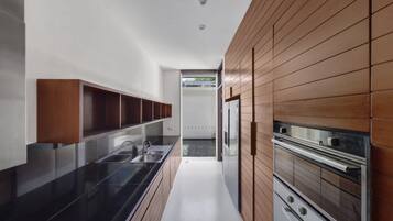 A modern kitchen with a black countertop, wooden cabinets, and stainless steel appliances.