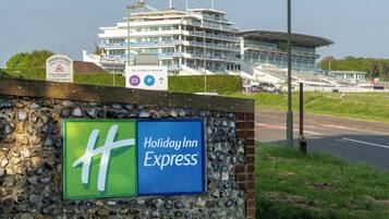 Placa do Holiday Inn Express com uma parede de pedra e um edifício grande ao fundo.
