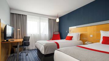 Habitación de hotel con dos camas, un escritorio con computadora, una silla y un teléfono.