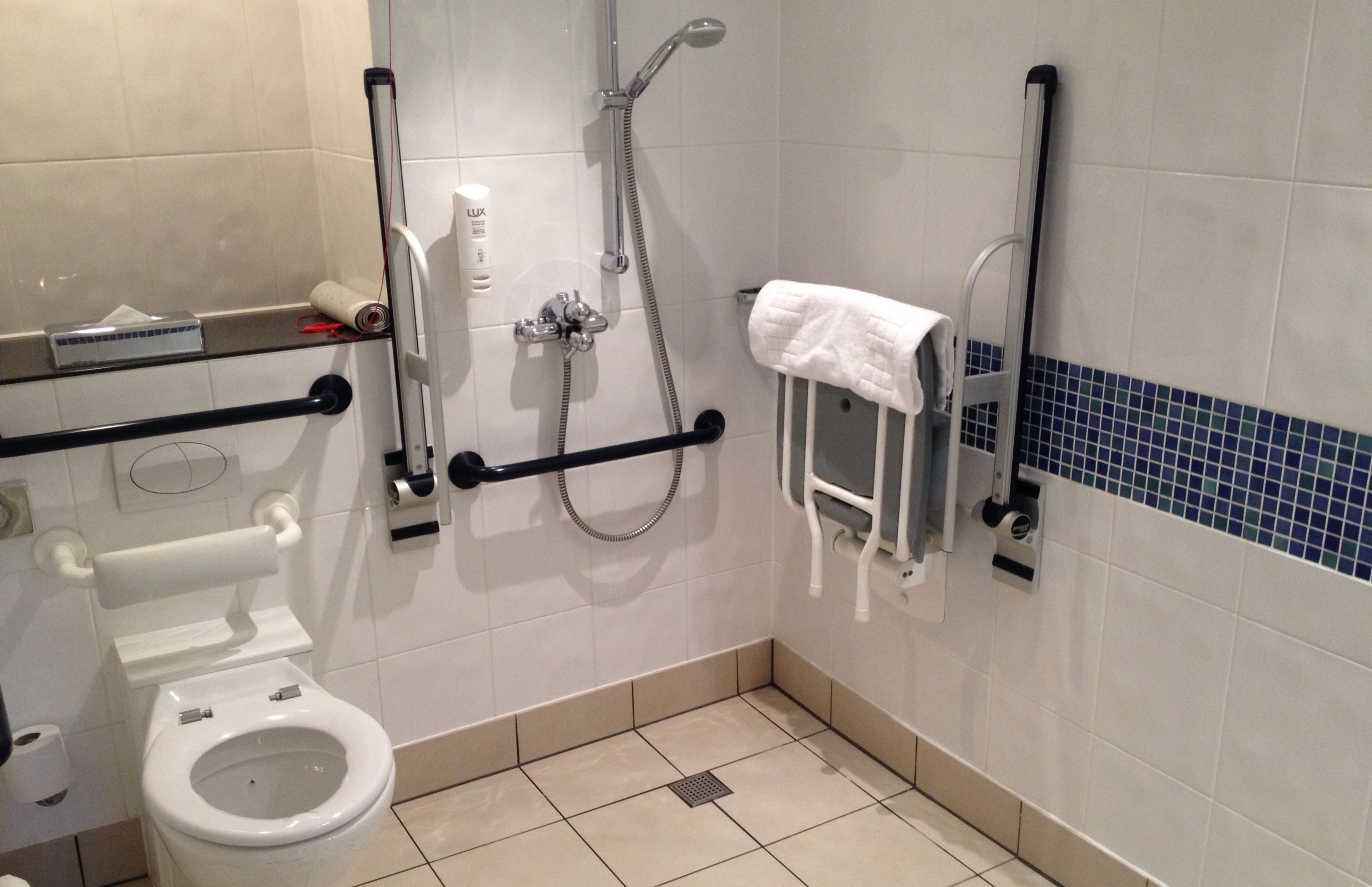 Un baño pequeño y moderno con inodoro, ducha y secamanos.