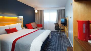 Een hotelkamer met een bed, een bureau, een stoel, een televisie en een rode speaker.