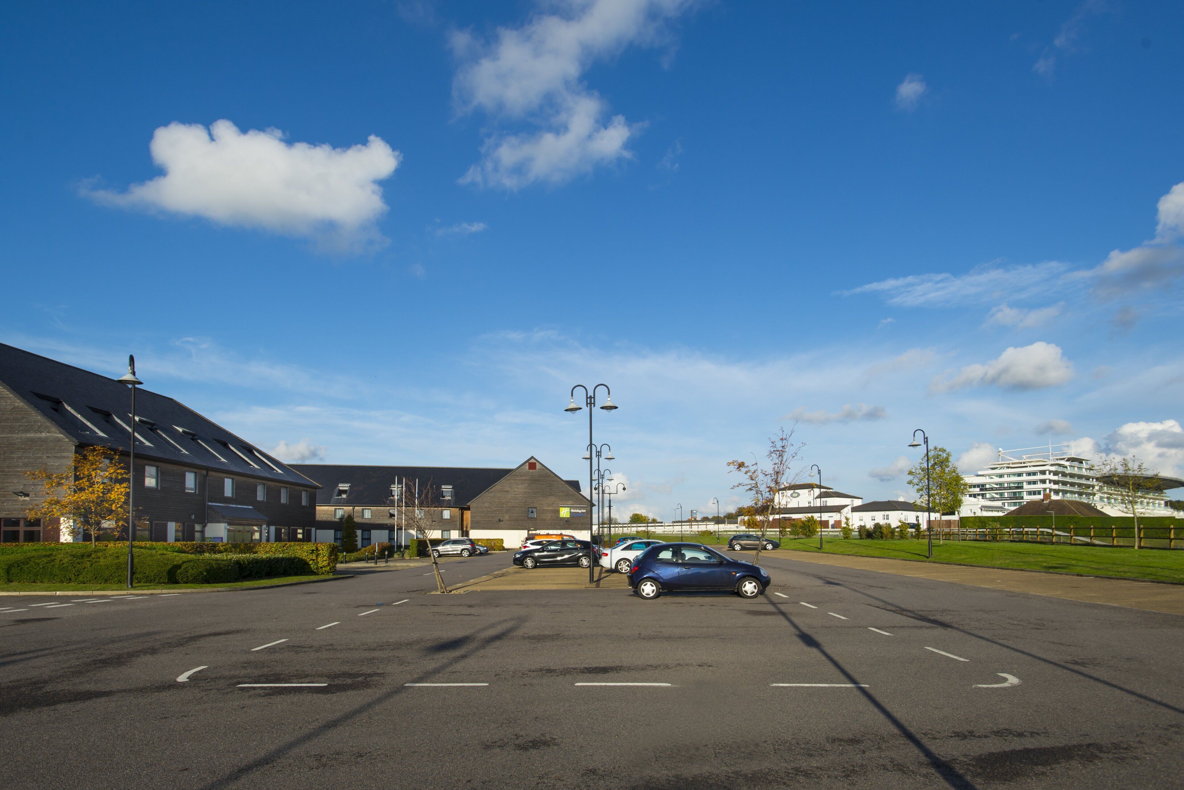 A parking lot with cars, a building with a sloped roof, and a clear sky.