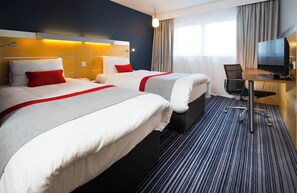 A hotel room with two beds, a desk with a television, and a window with curtains. - Holiday Inn Express London-Epsom Downs by IHG (Epsom)